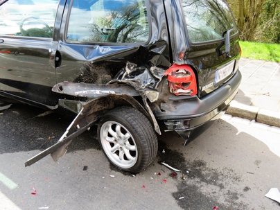 Rear-end damage to a black SUV after a car accident on a city street.